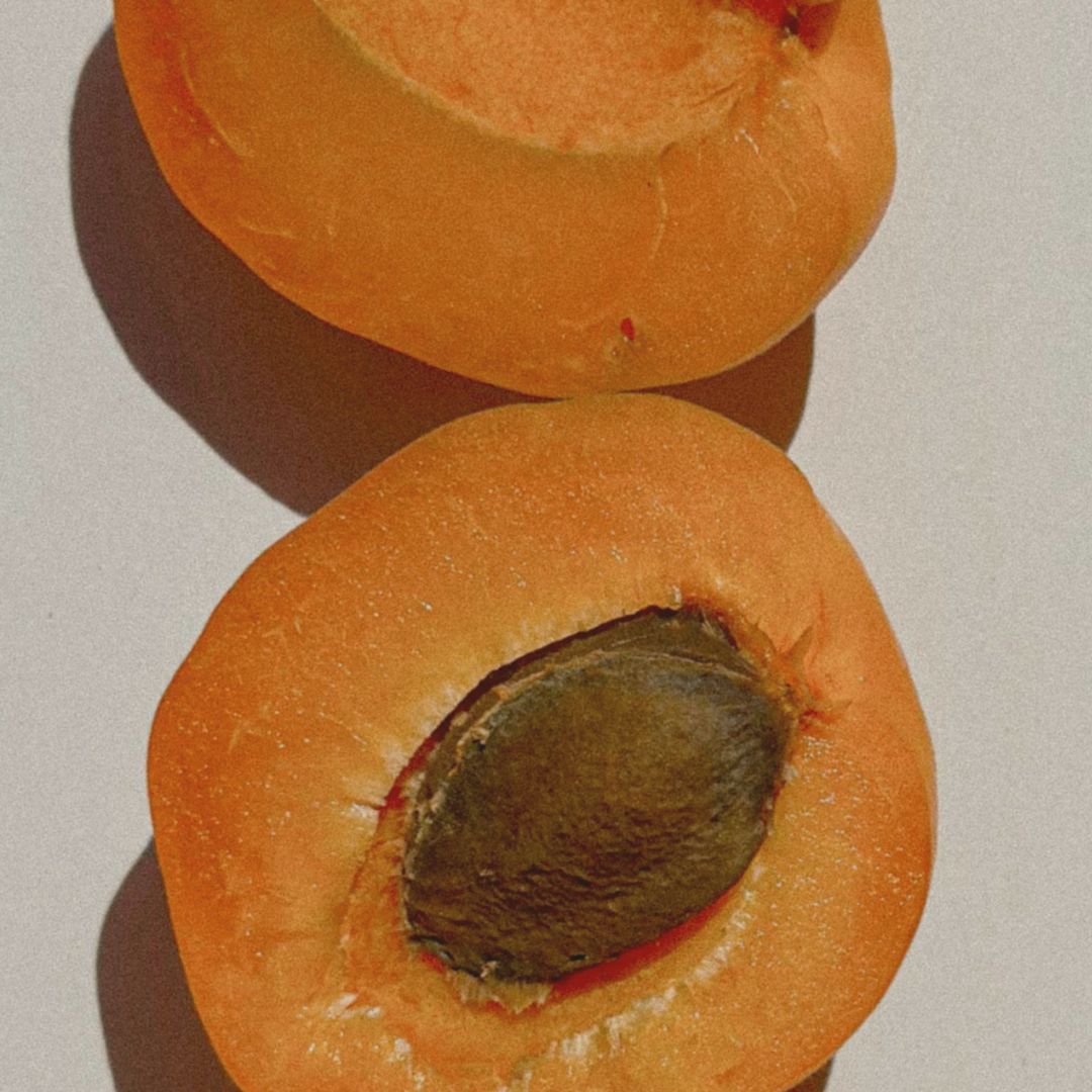 Två halvor av aprikosfrukt där kärnan syns tydligt, symbol för aprikoskärnolja som ingrediens i Me Animas naturliga hudvård