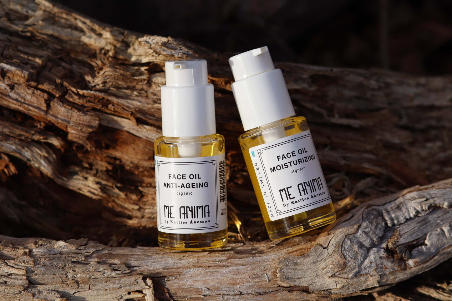 Me Anima Face Oil Anti-Ageing och Face Oil Moisturizing placerade på naturligt trä – ekologiska ansiktsoljor som mjukgör, återfuktar och stärker huden.