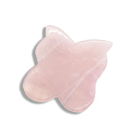 Gua Sha fjäril i rosenkvarts – ett massageverktyg som används för att stimulera blodcirkulationen, minska svullnad och ge huden ny lyster. Den mjuka fjärilsformen gör den idealisk för ansikte och hals.