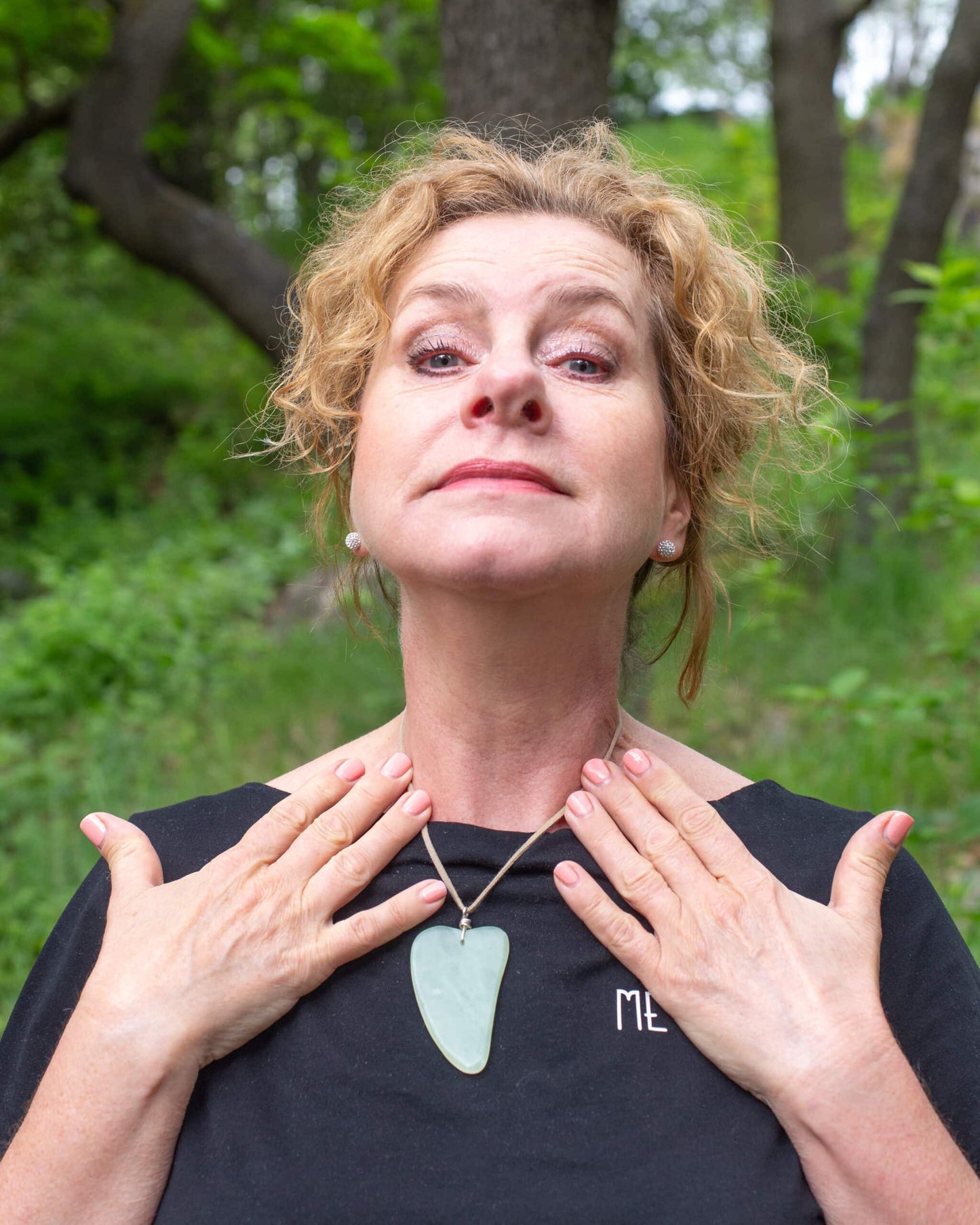 Katties Åkesson grundare av Me Anima visar halsövning för ansiktsgympa i naturmiljö
