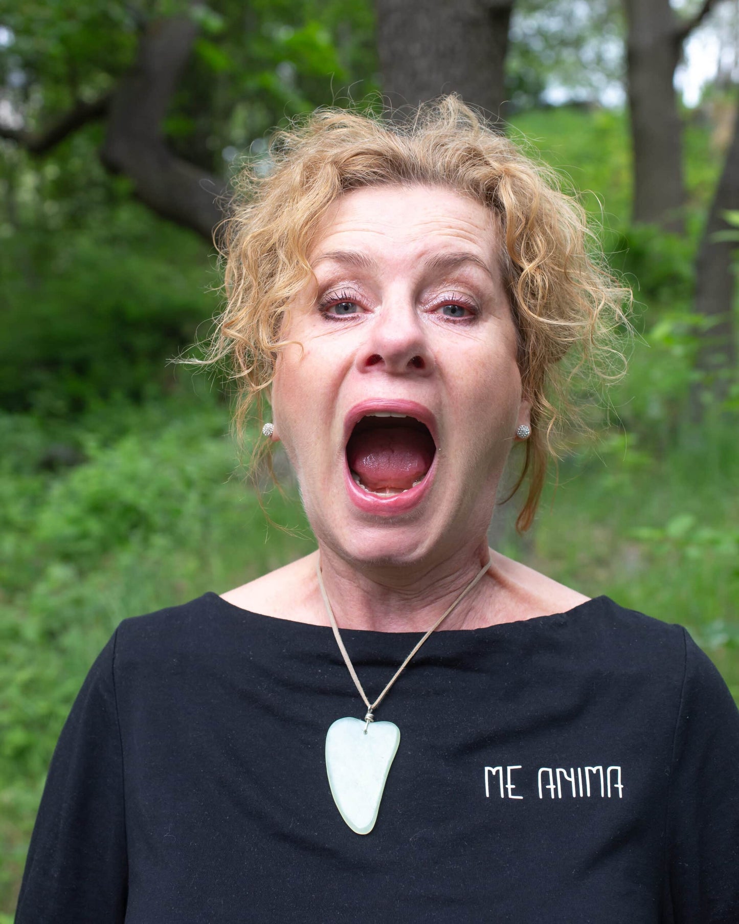 Katties Åkesson grundare av Me Anima visar munövning för ansiktsgympa i naturmiljö