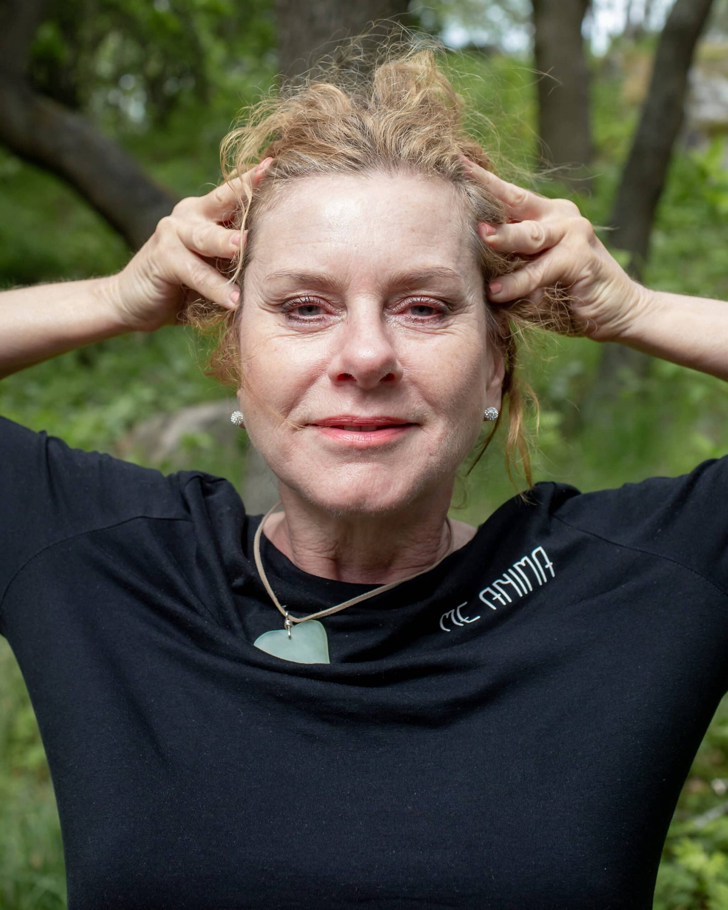 Katties Åkesson grundare av Me Anima visar pannövning för ansiktsgympa i naturmiljö