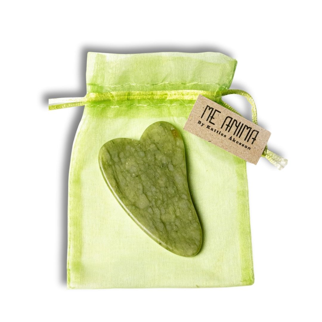 Me Anima Gua Sha i hjärtform av grön jade i ljusgrön tygpåse – verktyg för ansiktsmassage som stimulerar blodcirkulation och ger lyster.