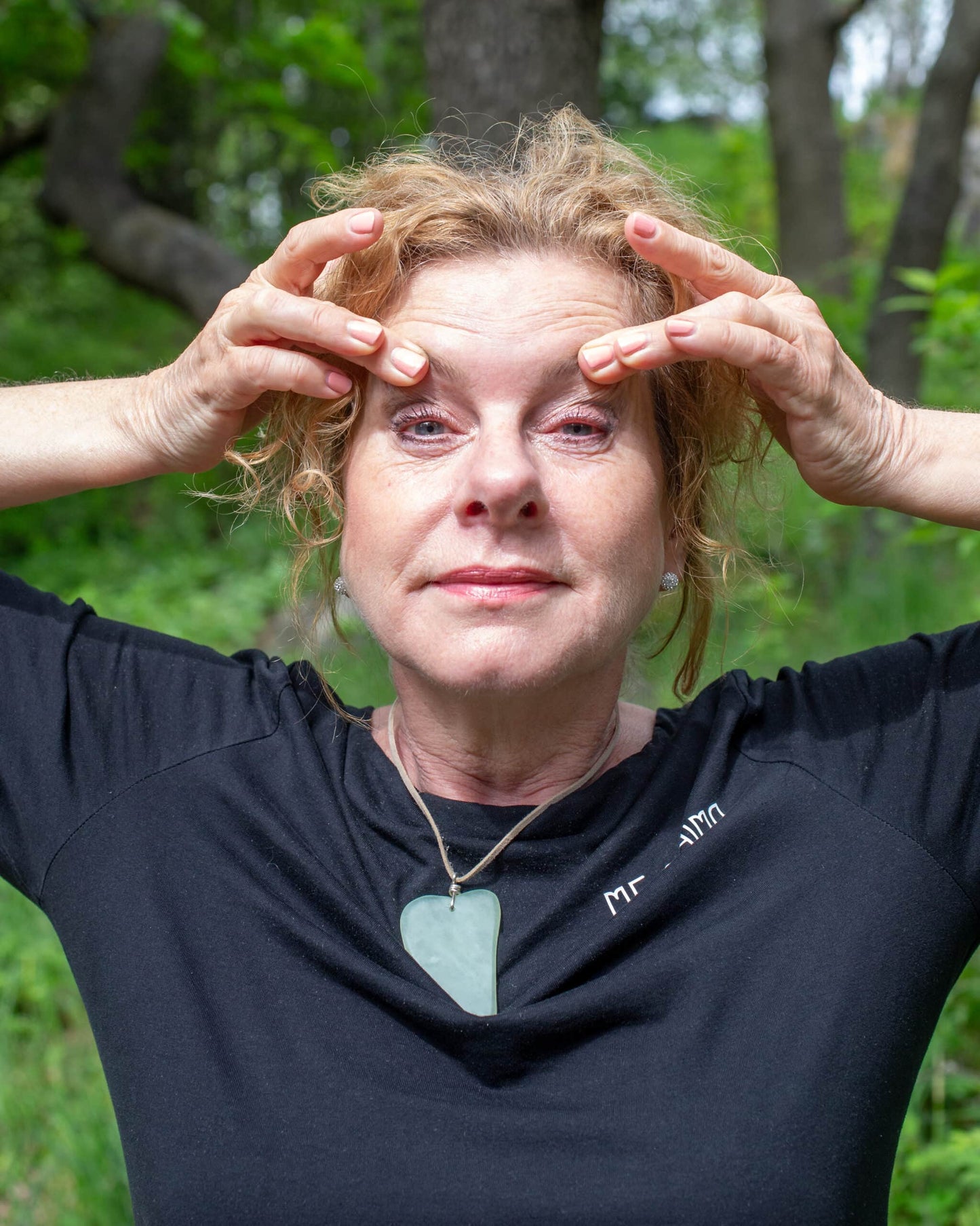 Katties Åkesson, grundare av Me Anima, visar ansiktsgympa och lymfmassage för att främja cirkulation och naturlig hudhälsa, iförd Gua Sha-hänge i grön sten.