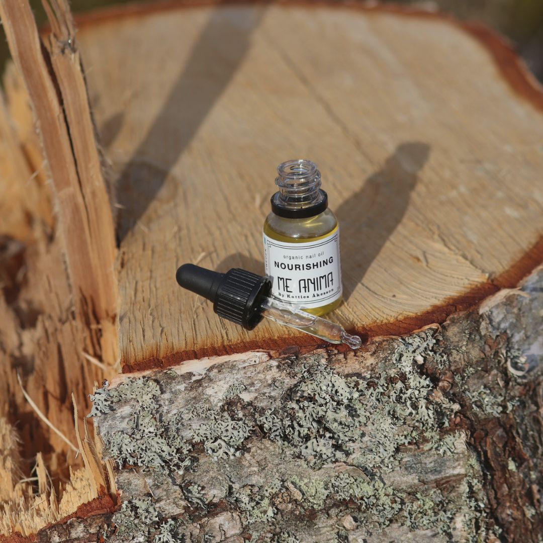 Me Anima nagelolja Myrrha med pipett placerad på en trädstubbe i solljus