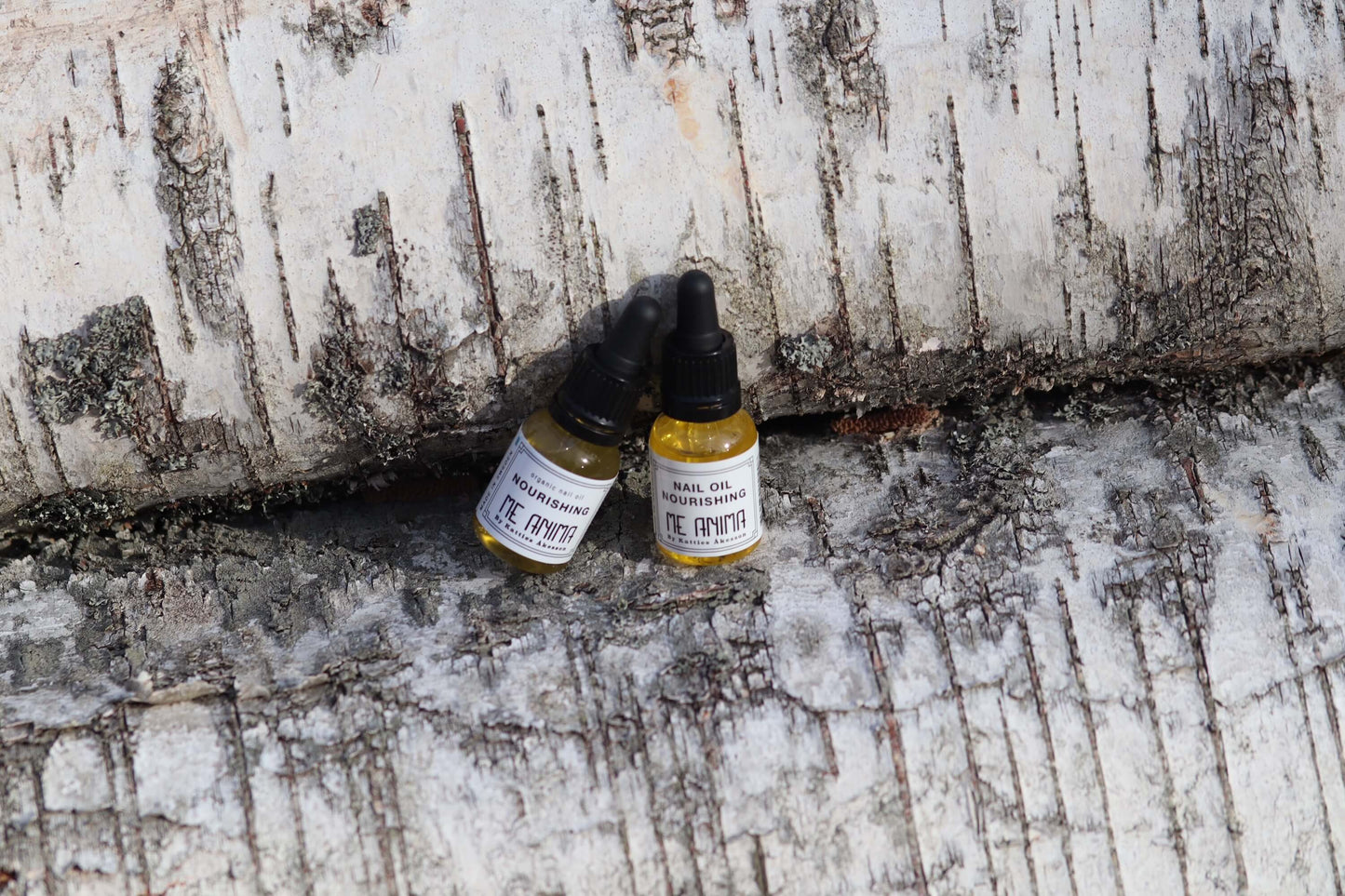 Me Animas Nail Oil Nourishing placerad på björkstam i naturlig miljö – ekologisk nagelolja som vårdar och stärker naglar och nagelband.